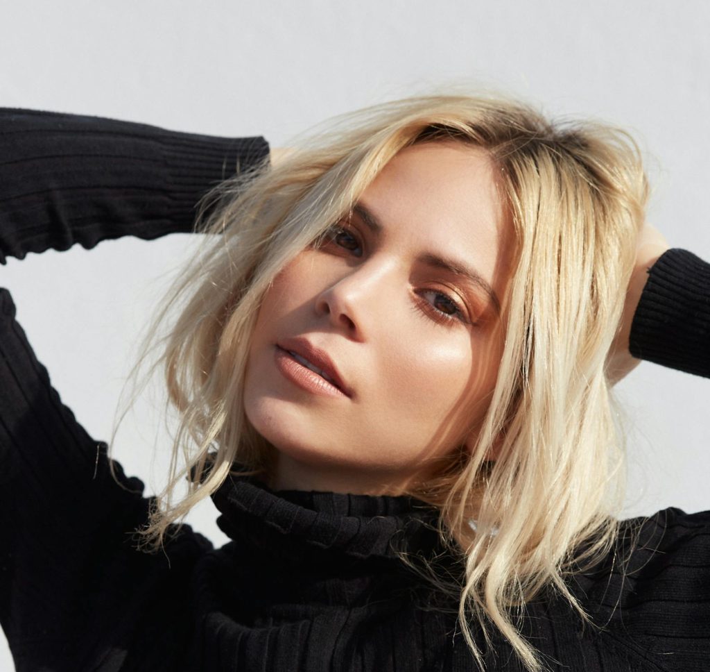 Elegant portrait of a young blonde woman in a black sweater, showcasing fashion and beauty.